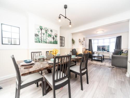 a dining room and living room with a table and chairs at Spacious 4 Bed House Free Parking Near Station - Pass the Keys in Bexleyheath