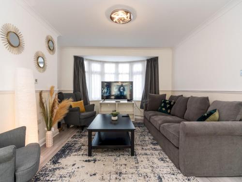 a living room with a couch and a table at Spacious 4 Bed House Free Parking Near Station - Pass the Keys in Bexleyheath