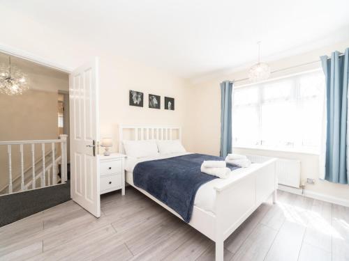 a white bedroom with a bed and a window at Pass the Keys Spacious 4 Bed House Free Parking Near Station in Bexleyheath