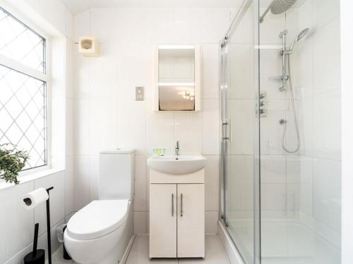 a bathroom with a toilet and a sink and a shower at Pass the Keys Spacious 4 Bed House Free Parking Near Station in Bexleyheath