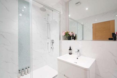 La salle de bains blanche est pourvue d'une douche et d'un lavabo. dans l'établissement Modern 3 bed Entire House, Gym & Underfloor Heating, à Hersham
