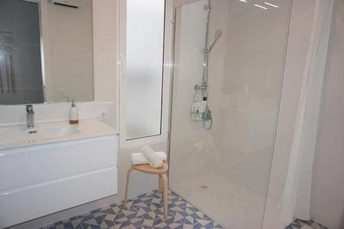 een badkamer met een douche en een kruk naast een wastafel bij Casa de pueblo en centro de Ondara recién reformada in Ondara