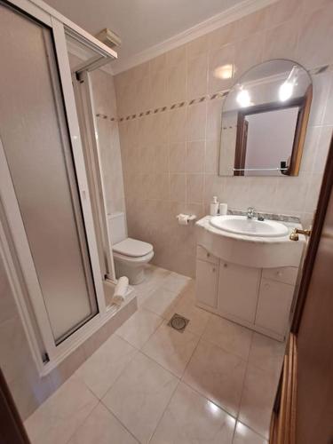 a bathroom with a sink and a toilet and a mirror at Ocean Gardens in Caniço