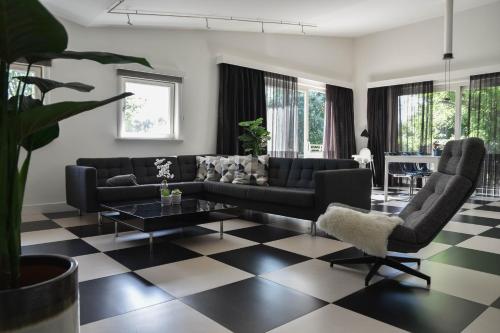 a living room with a black couch and a checkered floor at Spacious Comfort Villa Vera with hottub in Zeewolde