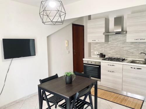uma cozinha com uma mesa e uma televisão numa cozinha em Defa Apartment em Giardini Naxos