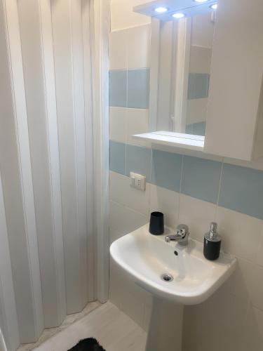 uma casa de banho com um lavatório branco e um espelho. em Defa Apartment em Giardini Naxos