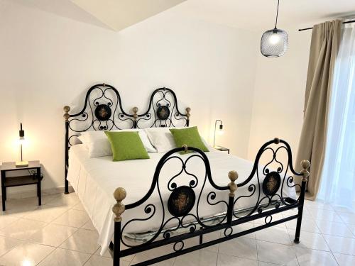 a bedroom with a black and white bed with green pillows at Defa Apartment in Giardini Naxos