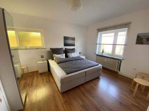 a bedroom with a bed and a wooden floor at FEDDERSEN LIVING Große Ferienwohnung - Garten - Terrasse - Smart TV - Netflix in Brunsbüttel