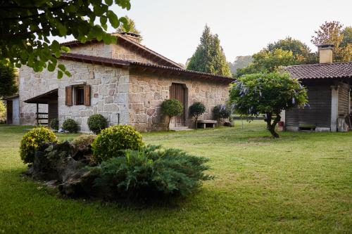 una vieja casa de piedra en un patio con un árbol en CASA DO COMBRO, en Ponteareas