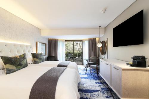 a hotel room with a large bed and a flat screen tv at Vineyard Hotel in Cape Town