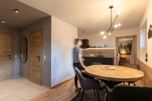 a man walking through a living room with a table at Landhaus Riepler in Wagrain