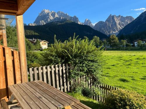 a wooden bench on a porch with mountains in the background at Le Crode in Sesto