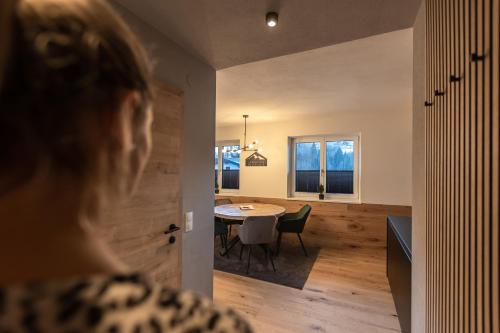 a woman looking at a dining room and living room at Landhaus Riepler in Wagrain