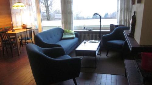 sala de estar con sofá azul, sillas y mesa en Ferienwohnung 11 mit Aussicht und Kamin, en Sankt Andreasberg