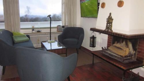sala de estar con 2 sillas y chimenea en Ferienwohnung 11 mit Aussicht und Kamin, en Sankt Andreasberg
