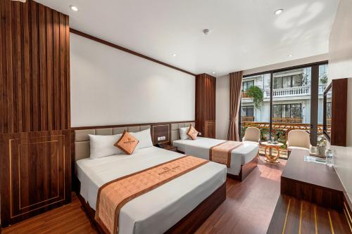 a hotel room with two beds and a desk at Harmony HaLong Hotel in Ha Long