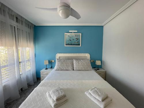 um quarto azul com uma cama e uma ventoinha de tecto em Apartamento a un minuto de la playa de Levante em Benidorm