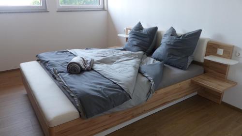 uma cama com lençóis cinzentos e almofadas em Ferienwohnung Steger em Mattsee