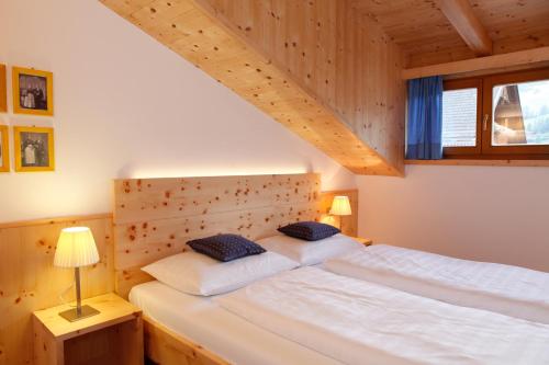 a bedroom with a white bed with a wooden headboard at Christophorus Mountain Residence in San Vigilio Di Marebbe