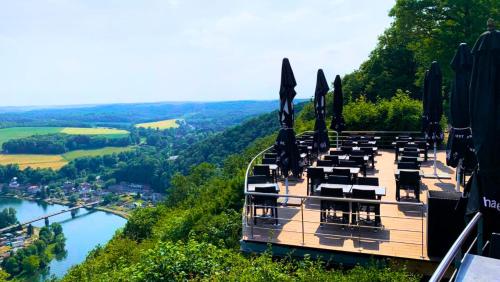 een restaurant aan de rand van een berg met uitzicht op een rivier bij LES 7 MEUSES - Restaurant & Hébergements HÔTELIERS - INSOLITES - WELLNESS - GÎTES in Profondeville