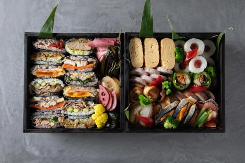Kawajiriにある海辺の古民家ホテル　奥能登じろんどん（一棟貸宿）の異なる種類の寿司が入った2つの黒いトレー
