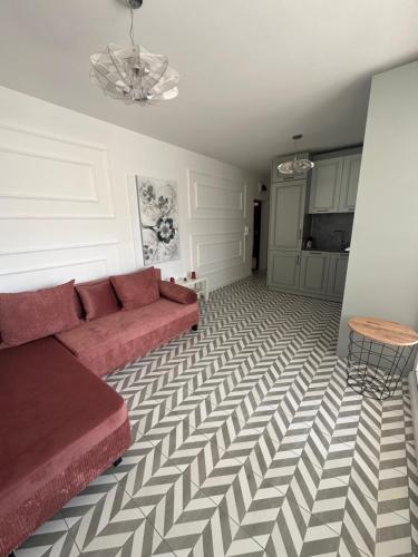ein Wohnzimmer mit einem roten Sofa und einem karierten Boden in der Unterkunft Abel Apartment in Pomorie