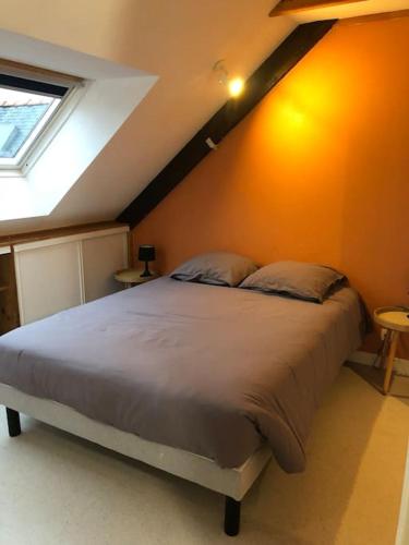 - une chambre avec un grand lit et un mur orange dans l'établissement Plaisancier by Póm, à Lorient