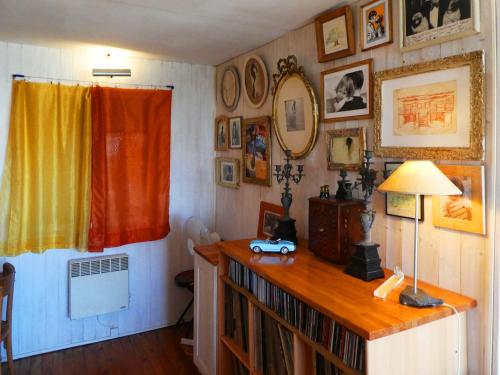Zimmer mit Bücherregal mit Lampe und Bildern an der Wand in der Unterkunft UN CHALET EN BOIS A LA PLAGE in Gruissan