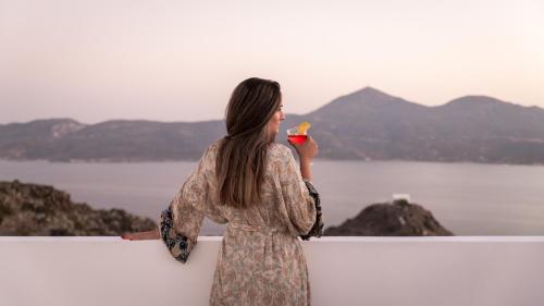 a woman standing against a wall holding a drink at Studios Betty in Plaka Milou