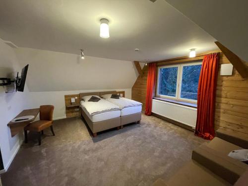 a bedroom with a bed and a desk and a window at Berggasthof Tönsblick in Oerlinghausen