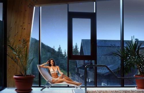 a woman sitting in a chair in a window at Wellness Hotel Chopok in Demanovska Dolina