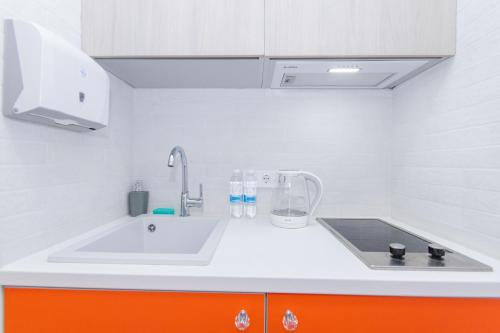 cocina con fregadero y armario de color naranja en MYFREEDOM Апартаменти метро Шулявська en Kiev