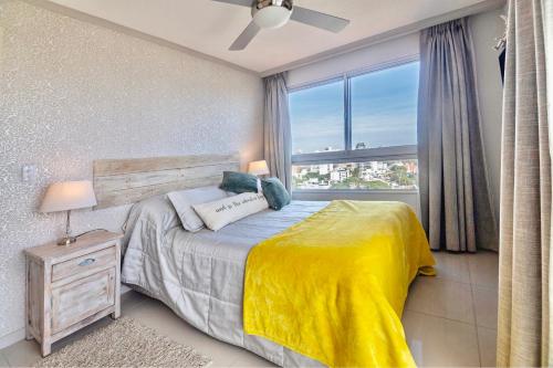 1 dormitorio con 1 cama con manta amarilla y ventana en Oceana Suites en Ocean Drive, con piscina interior climatizada, en Punta del Este
