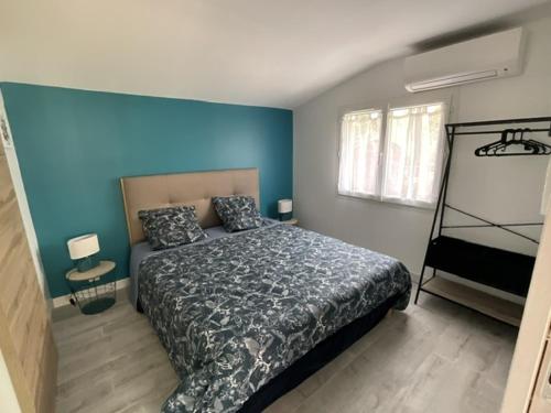 une chambre avec un lit et un mur bleu dans l'établissement Maison sous les chênes, à Le Gua