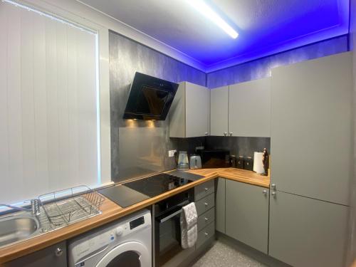 a kitchen with a washing machine and a blue ceiling at Spalding Town Centre Luxury Private Apartment in Spalding