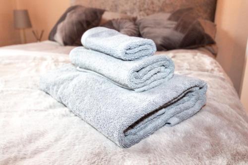 a pile of towels sitting on top of a bed at Spalding Town Centre Luxury Private Apartment in Spalding