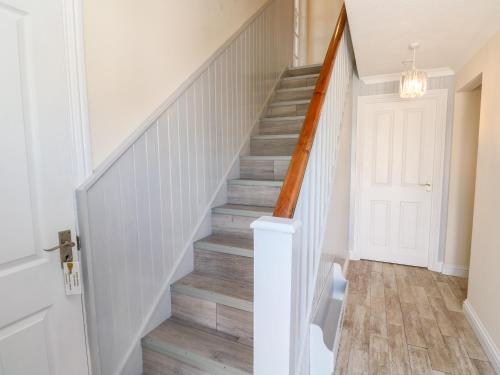 a staircase in a home with white walls and wood floors at The Mariners in Helston
