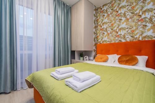 Un dormitorio con una cama verde con toallas. en MYFREEDOM Апартаменти метро Шулявська en Kiev