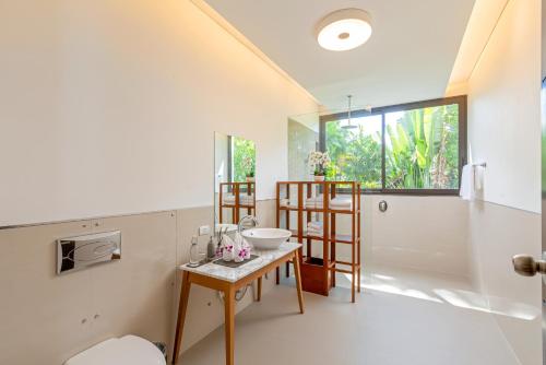 een badkamer met een wastafel en een tafel in een kamer bij Villa Arun in Phuket