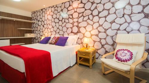 a bedroom with a bed and a chair in a room at Kembali Hotel Porto de Galinhas - Adults Only in Porto De Galinhas