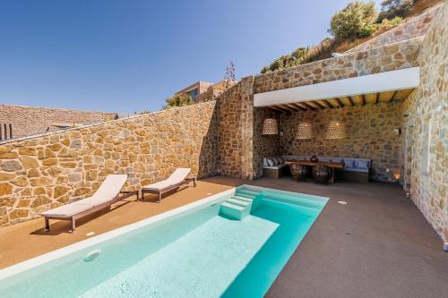 a house with a swimming pool and a stone wall at Luxury Villa Gialova Lagoon with Private Pool in Gialova