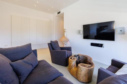 a living room with a couch and chairs and a flat screen tv at Luxury Villa Gialova Lagoon with Private Pool in Gialova