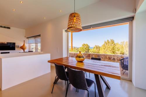 a dining room with a table and chairs and a large window at Luxury Villa Gialova Lagoon with Private Pool in Gialova