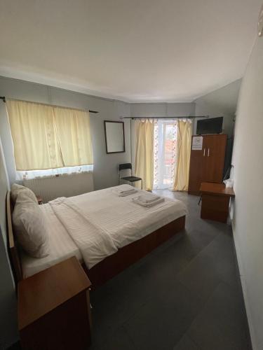 a bedroom with a large bed and two windows at Pensiunea Mario in Arad