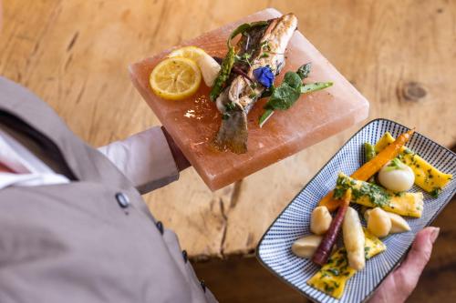 a person holding a plate of food on a cutting board at Small Luxury Hotel Goldgasse in Salzburg