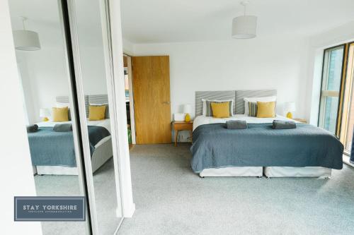 a bedroom with two beds and a mirror at Stay Yorkshire IQ 4 Blonk Street in Sheffield