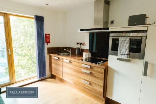 a kitchen with wooden cabinets and a large window at Stay Yorkshire IQ 4 Blonk Street in Sheffield