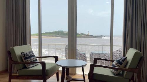 a room with two chairs and a table and a view of the ocean at Praveg Beach Resort Diu, Chakratirth Beach in Diu