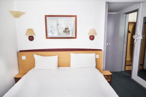 um quarto com uma grande cama branca e 2 almofadas em Campanile Hotel Runcorn em Runcorn