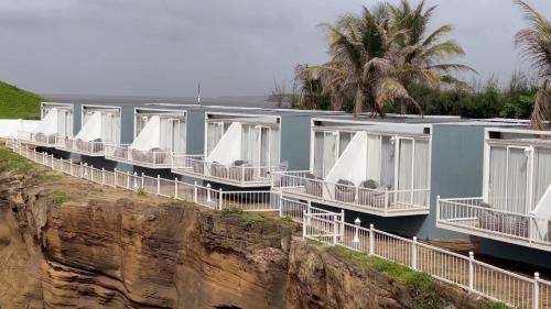 a row of houses on a cliff next to the ocean at Praveg Beach Resort Diu, Chakratirth Beach in Diu